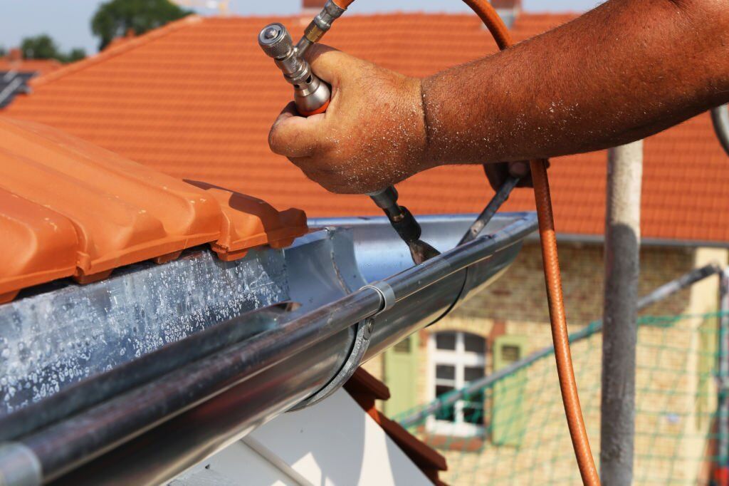 Roofer doing plumbing work on a gutter